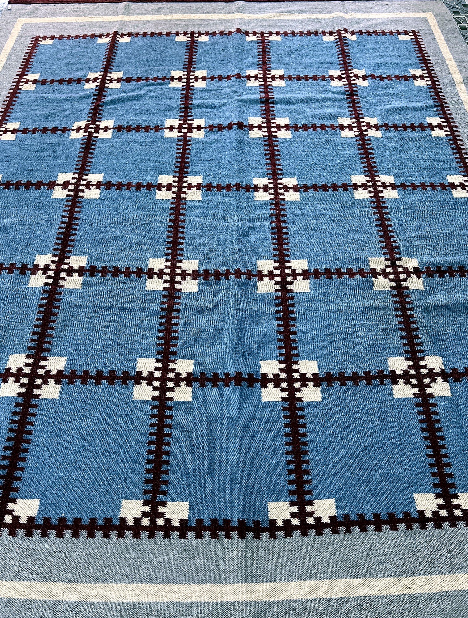Angled full-length view of the handwoven cobalt blue kilim rug with maroon grid pattern | The Rugs Curator — Pakistani Premium Rugs