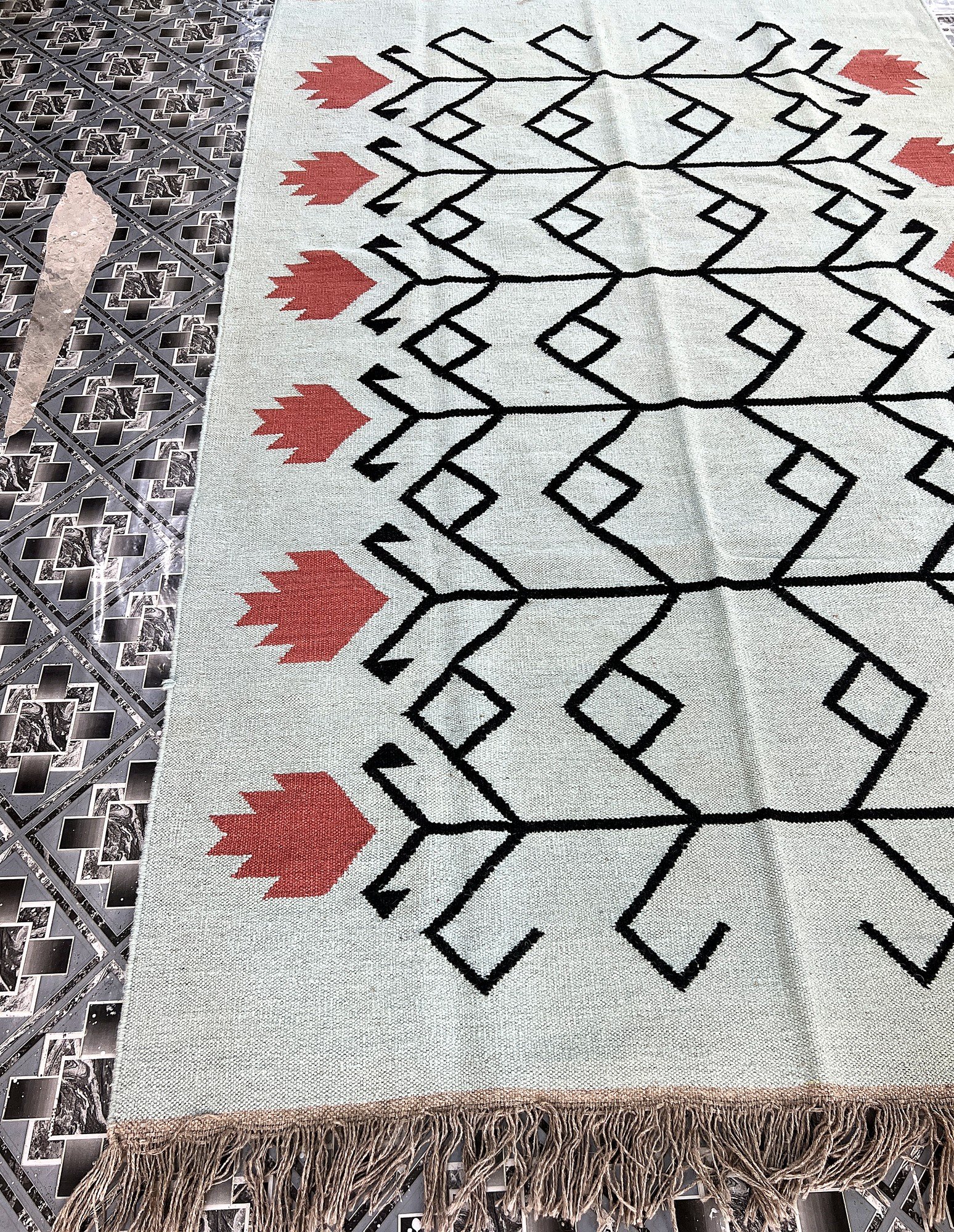 Handwoven sage green kilim rug with black tribal motif and coral accents | The Rugs Curator — Pakistani Premium Rugs