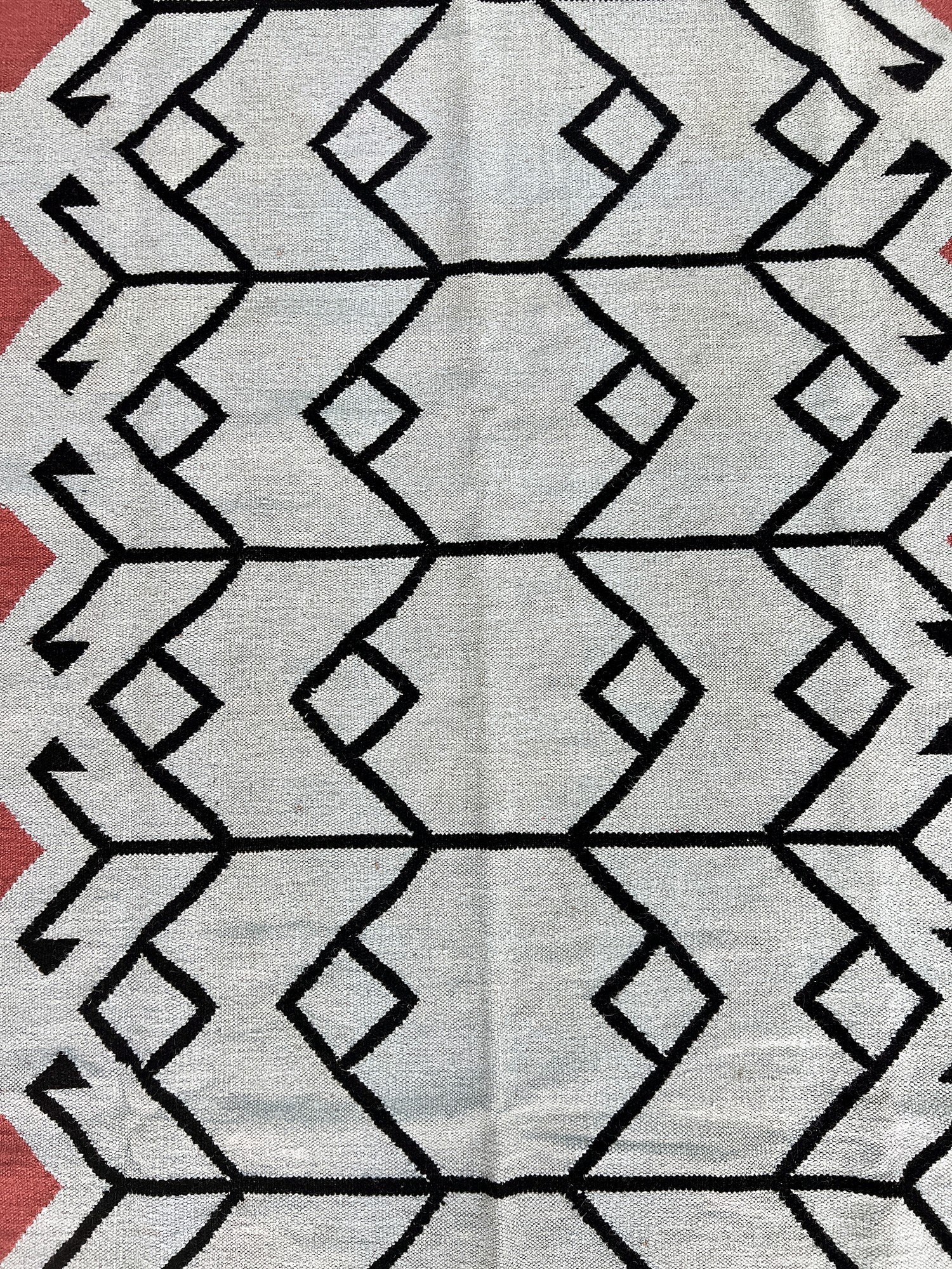 Close-up of the flatweave texture on the sage green kilim rug with black tribal motif | The Rugs Curator — Pakistani Premium Rugs