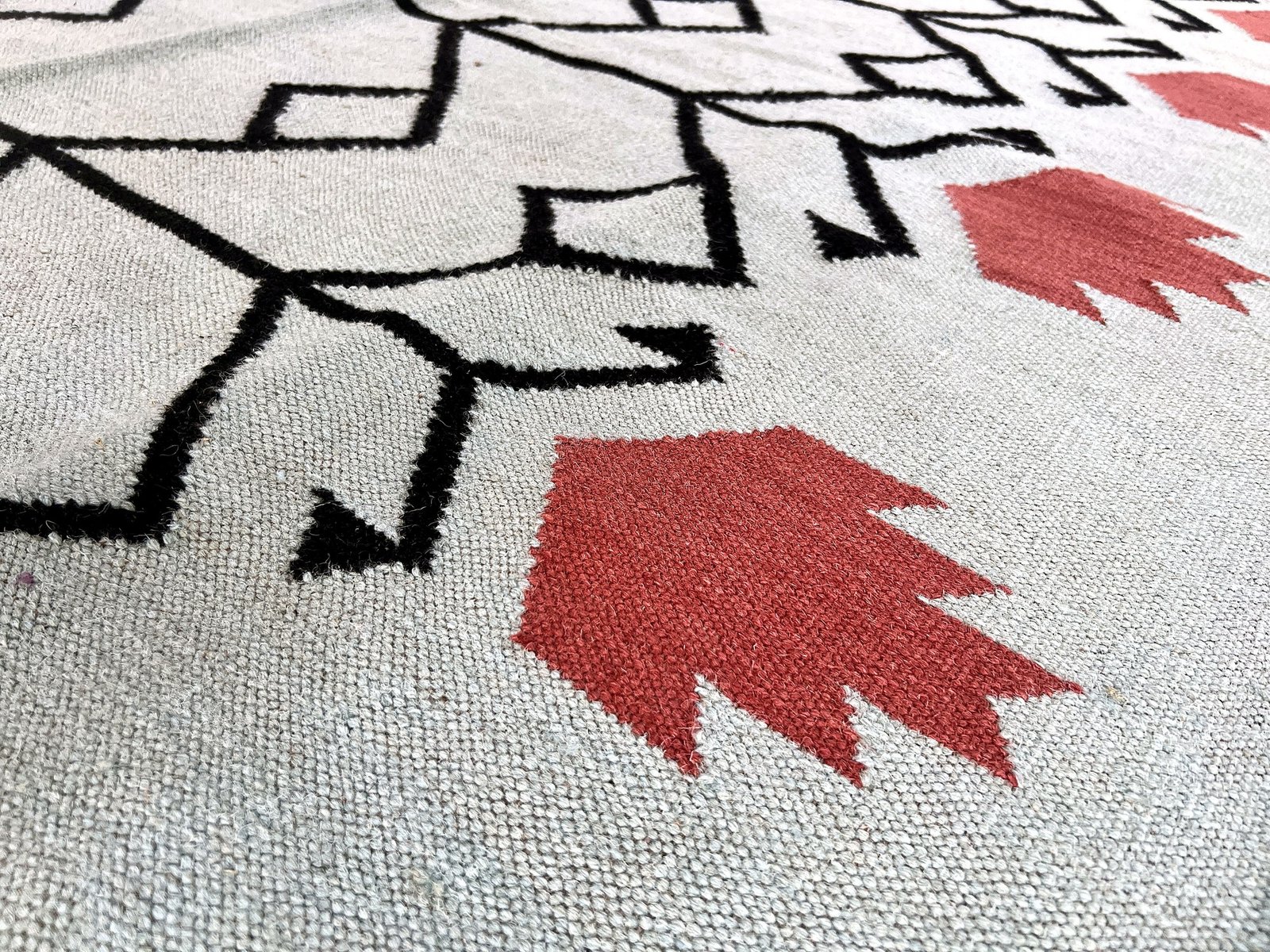 Close-up of the coral accent stripes and weave on the sage green tribal motif kilim rug | The Rugs Curator — Pakistani Premium Rugs