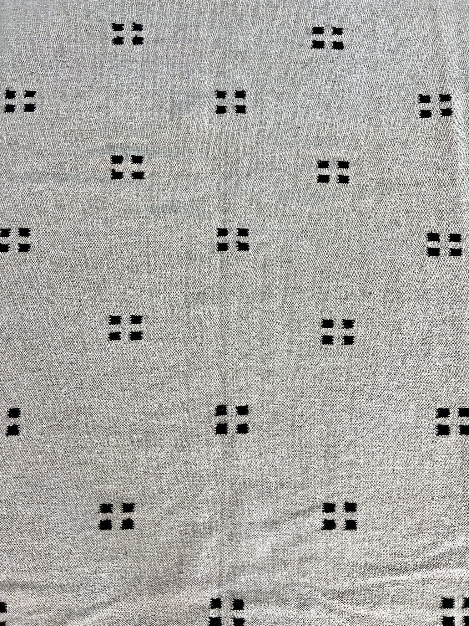Close-up of the flatweave texture on the ivory kilim rug with black square-dot pattern | The Rugs Curator — Pakistani Premium Rugs