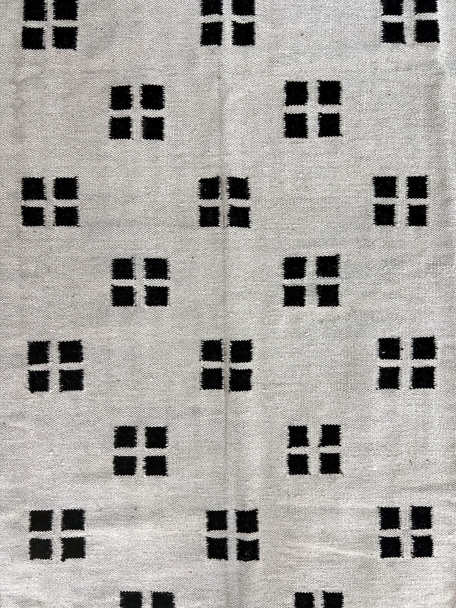 Close-up of the flatweave texture on the ivory kilim rug with black confetti dot pattern | The Rugs Curator — Pakistani Premium Rugs