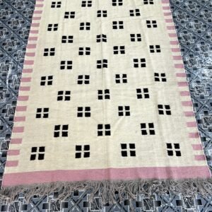 Handwoven ivory kilim rug with black confetti dot pattern and pink border | The Rugs Curator — Pakistani Premium Rugs