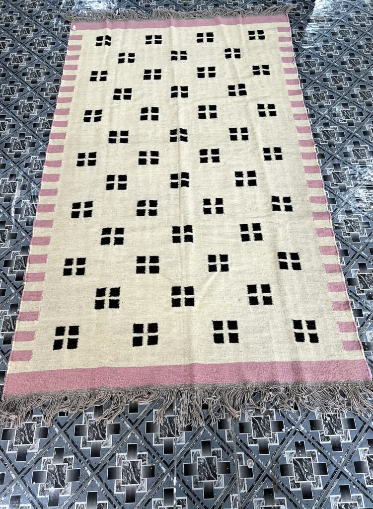 Handwoven ivory kilim rug with black confetti dot pattern and pink border | The Rugs Curator — Pakistani Premium Rugs